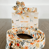 A floral-patterned dog collar and leash with a flower-shaped accessory, along with a box labeled "SNIFF & DARK" featuring various dog breeds.