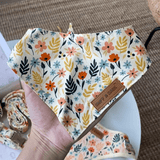 A hand holding a colorful floral bandana with a leather tag that says "SNIFF & DAB".